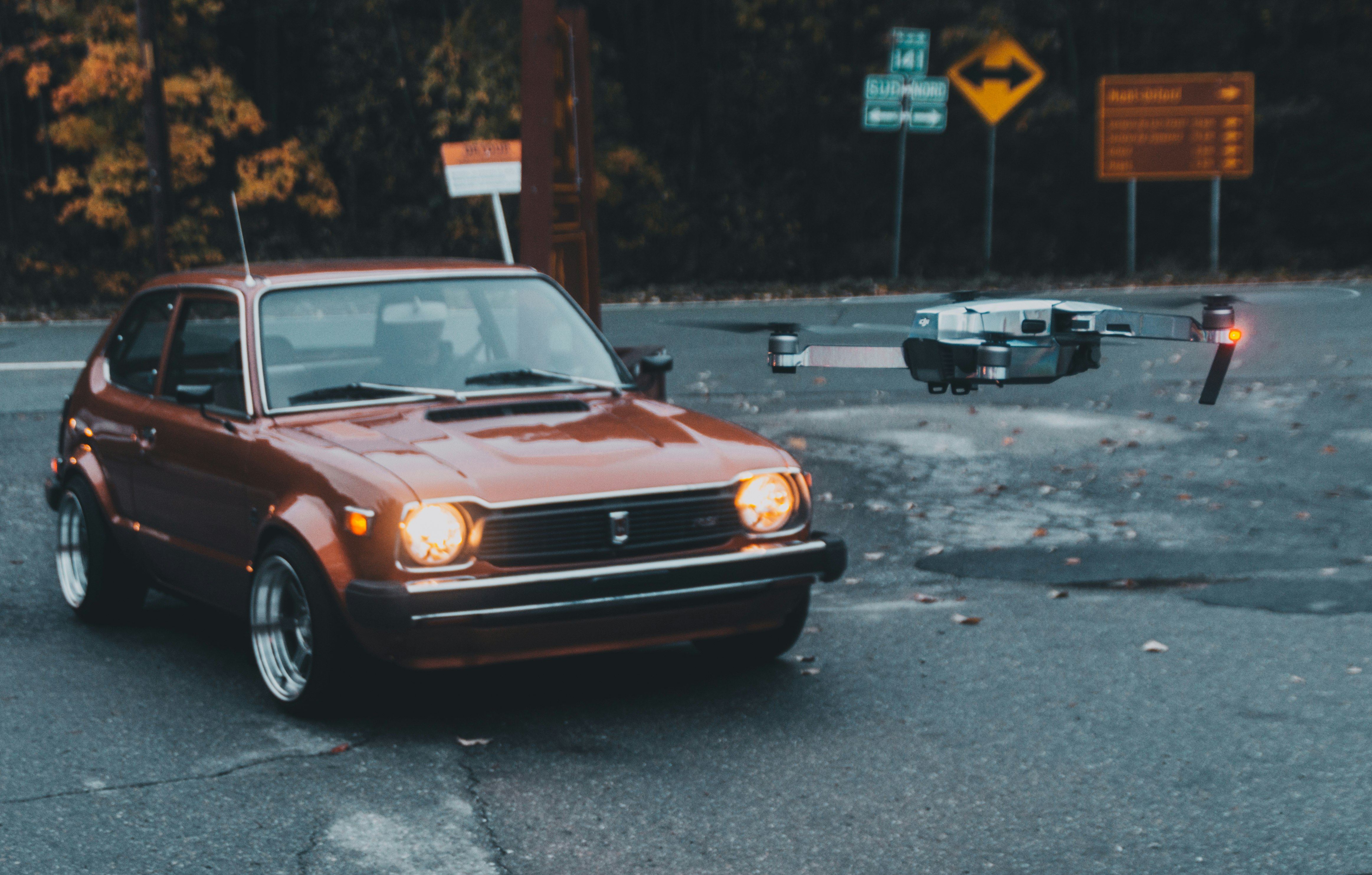 orange 3-door hatchback near flying drone